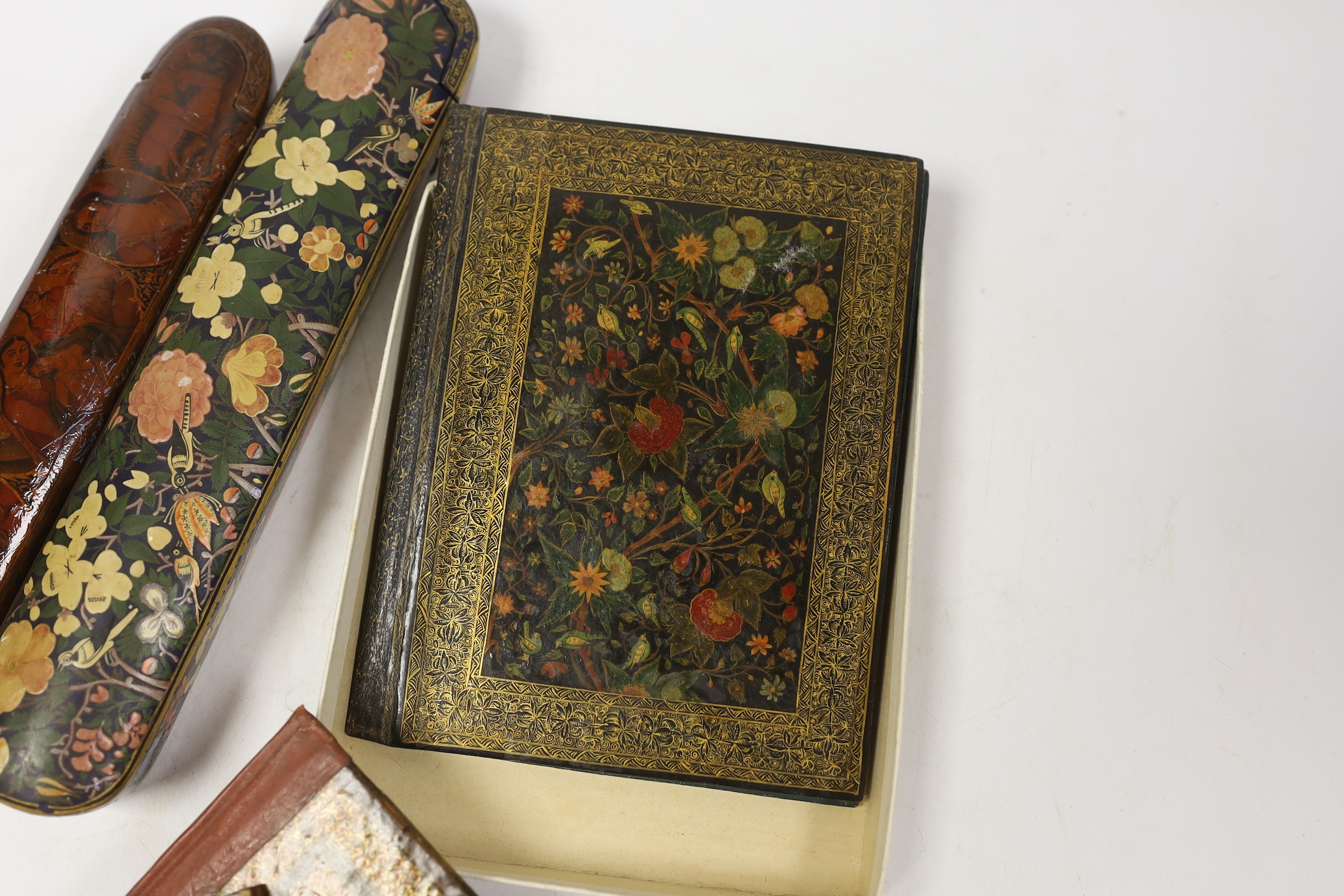 A Persian scribe’s pen box, painted with ladies and animals, another similar with printed floral decoration and other Persian and Kashmiri lacquer blotter /book covers largest cover 13.5 cm wide x 18cm high